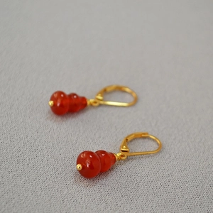 Detailed view of red agate gourd drop earrings with elegant golden leverback ear hooks