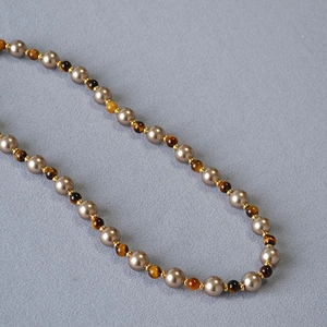 Vintage necklace with tiger eye stones and champagne pearls on grey fabric texture