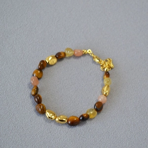 Detail of beaded necklace with tiger eye stones, pink beads, and golden metallic accents