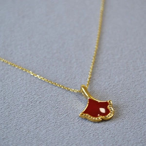 Collier feuille de ginkgo doré avec émail rouge et zircons blancs sur tissu gris clair