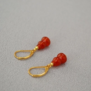 Detailed macro of red agate gourd earrings with elegant gold leverback hooks