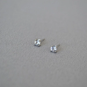 Macro shot of minimalist silver-plated four-prong stud earrings with clear round cubic zirconia
