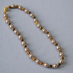 Detail of tiger eye beads and champagne pearls with a golden spherical clasp