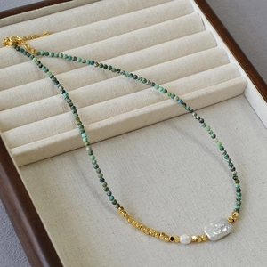 Detailed view of turquoise beaded necklace featuring a large baroque pearl and gold accents