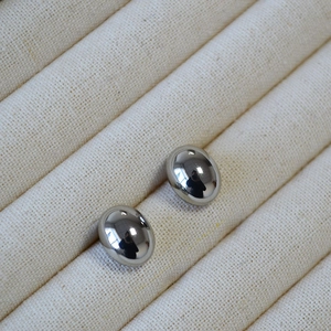 Minimalist silver oval stud earrings with polished mirror finish on a cream display tray