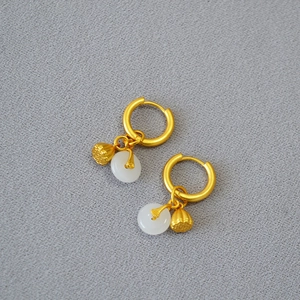Vue détaillée des boucles d'oreilles dorées avec boucle de jade blanc et pendentif lotus