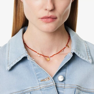 Detail of red beaded necklace with pearls and gold pendants on a model's neck
