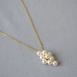 Détail d'une élégante chaîne dorée avec un pendentif en grappe de perles crème