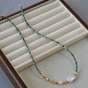 Detail of beaded necklace with turquoise stones, gold metal spacers and baroque pearls