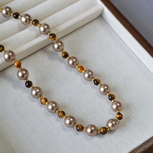 Vintage necklace with brown tiger eye stones and pearls on a display tray