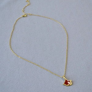 Détail macro du collier pendentif feuille de ginkgo en émail rouge et pierres brillantes