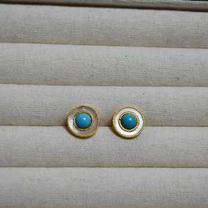 Detailed macro view of vintage round earrings with turquoise, pearl shell, and gold beads