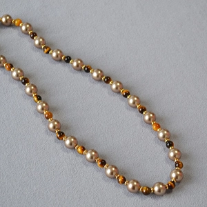 Detailed view of Tiger Eye stones and champagne pearls on a vintage beaded necklace