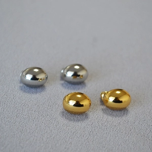 Detailed close-up of polished oval metallic stud earrings in gold and silver finishes