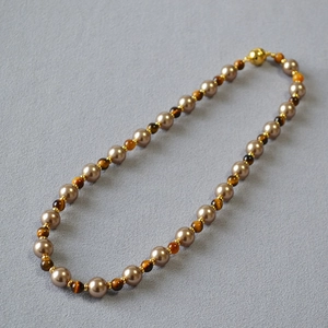 Detailed shot of tiger eye beads and champagne pearls with a golden magnetic clasp