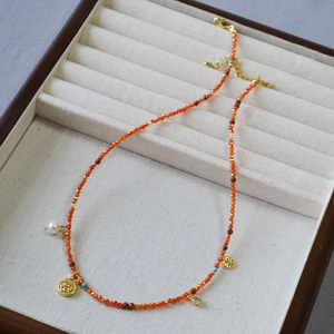 French retro beaded necklace with gold coins and pearl pendant on a beige jewelry tray