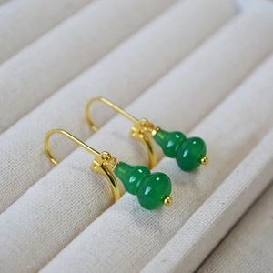 Close-up of green agate gourd earrings with gold hooks on a beige velvet jewelry display box