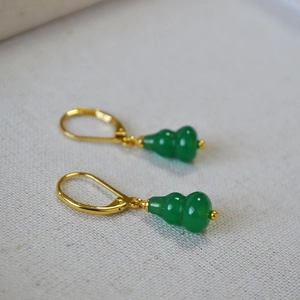 Detail of green agate gourd earrings with gold lever back hooks on white fabric