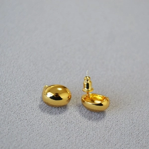 Macro shot of oval gold-plated brass stud earrings with smooth polished streamline finish