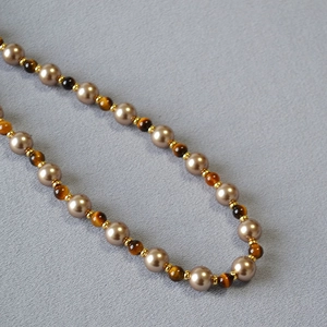 Close-up of tiger eye stones and champagne pearls on a vintage beaded necklace