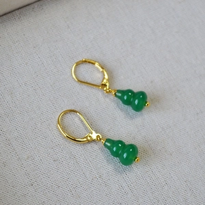 Detail of green jade gourd earrings with gold lever-back hooks on white fabric