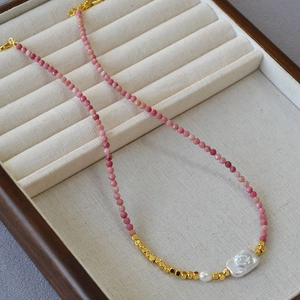 Baroque pearl necklace with pink gemstone beads and golden accents on a jewelry tray