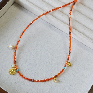 Detailed shot of red beads with gold coin pendant and pearl necklace accents