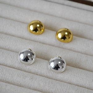 Macro shot of minimalist gold and silver hemisphere stud earrings on velvet tray