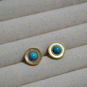 Detailed macro view of vintage turquoise stud earrings with white mother of pearl inlay