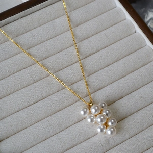 Collier doré élégant avec pendentif grappe de perles sur présentoir en velours beige