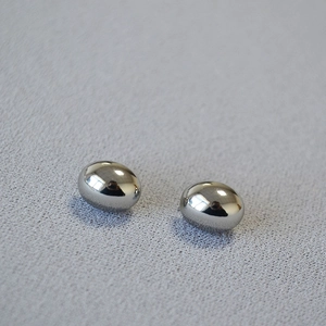 Macro shot of polished silver oval studs with a high-shine mirror finish and minimalist design