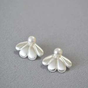 Boucles d'oreilles fleur argentée avec perle blanche et texture brossée sur tissu gris