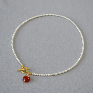 Detail of pearl necklace featuring gold OT toggle clasp and red agate heart pendant