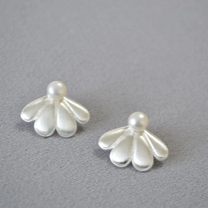 Boucles d'oreilles fleurs en argent brossé avec perles sur fond en tissu gris texturé