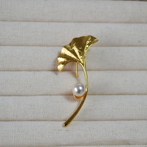 Ginkgo leaf brooch in gold finish with white pearl on beige jewelry display box