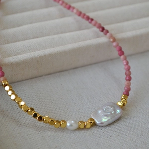 Handmade necklace with baroque pearl and turquoise beads on soft textile background
