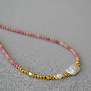 Macro shot of faceted pink mineral beads and baroque pearls on a handcrafted necklace