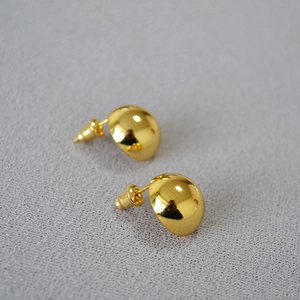 Macro detail of gold-plated dome earrings featuring a high-polish mirror finish texture