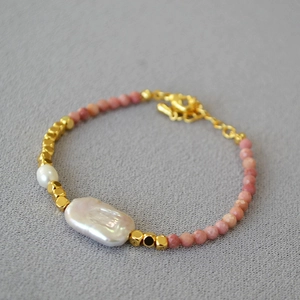 Detail of beaded necklace with pink stones, gold spacers and baroque pearl charm