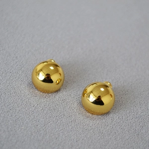 Minimalist high-polish golden hemisphere stud earrings on a dark textured background