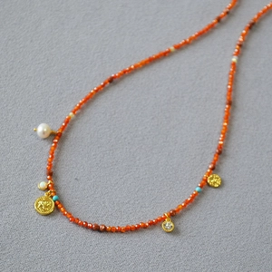 Detail of bohemian red stone beaded necklace with vintage gold coin pendants and pearls