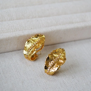 Macro detail of gold leaf stud earrings with fine texture and sparkling zircon inlay