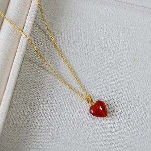 Minimalist gold necklace featuring a polished red heart agate pendant on a fine chain