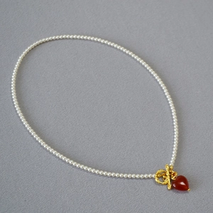Macro view of pearl necklace with gold OT buckle and red heart agate pendant