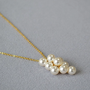 Détail d'un pendentif en perles en grappe avec élégante fine chaîne dorée de collier