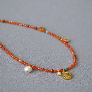 Detailed macro view of red faceted beads with pearl and vintage gold coin pendants