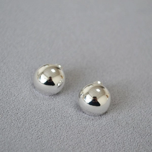 Macro shot of minimalist silver hemispherical stud earrings with a high-polished mirror finish