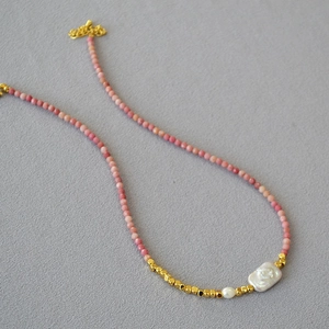 Detailed macro view of handmade turquoise and baroque pearl beaded necklace with gold clasp