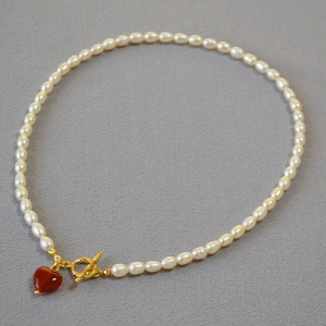Close-up of pearl necklace with golden OT clasp and red agate heart pendant