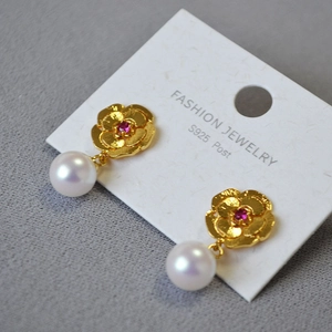 Detailed macro view of vintage flower earrings with pearl and red gemstone accents